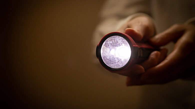 A person holding a lit-up flashlight.
