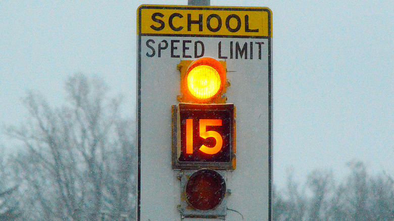 A lit speed limit sign indicating a limit of 15 mph in a school zone