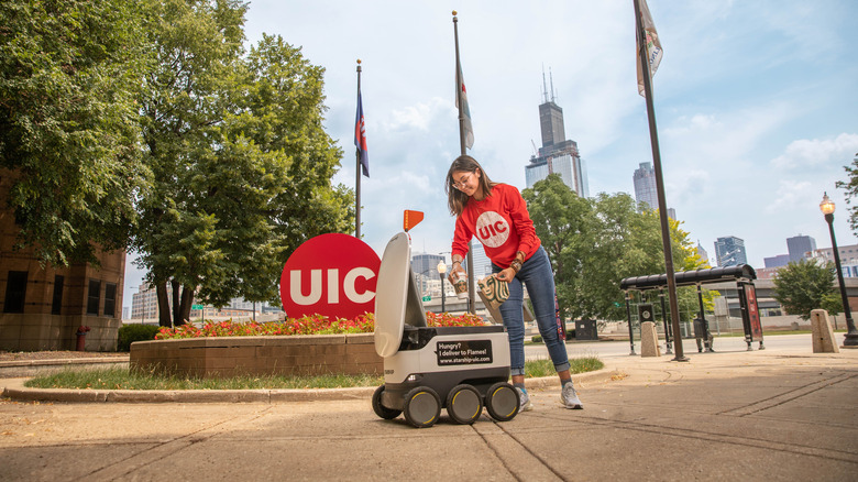 Campus student receiving food delivery from a robot 