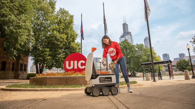 Campus student receiving food delivery from a robot