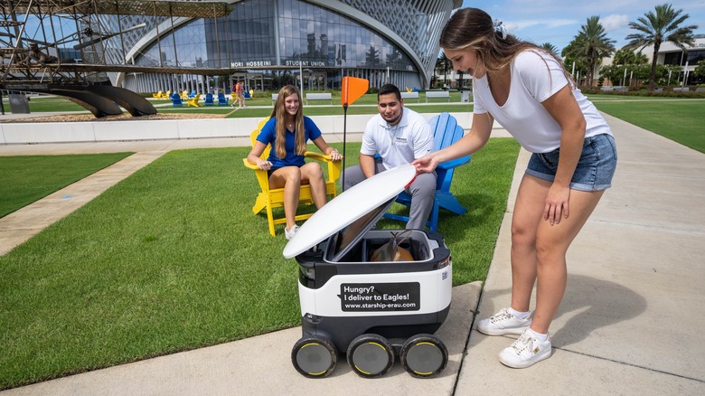 Campus student receiving food delivery from a robot