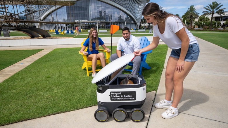 Campus student receiving food delivery from a robot 