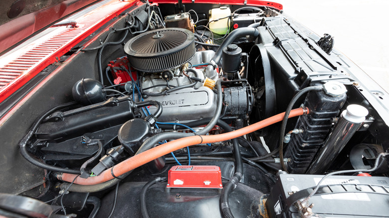 A Chevrolet 292-cubic inch inline-six in the engine bay of a red C/K series pickup from the 1960s.