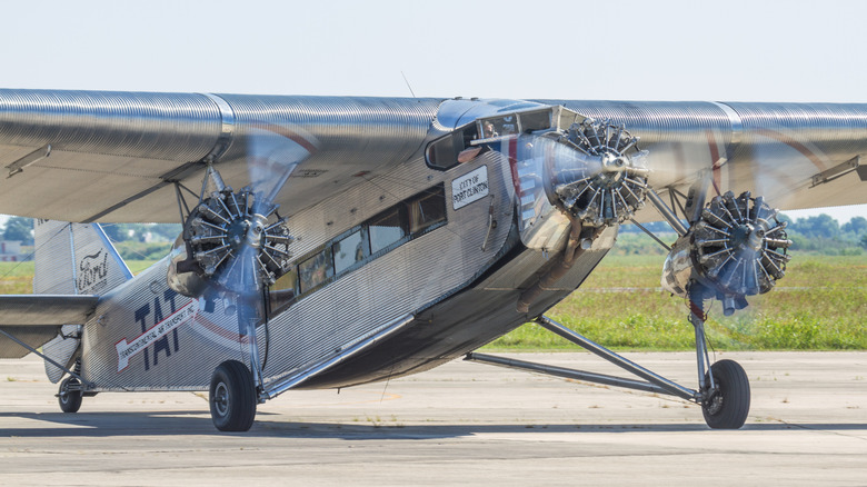 A Ford Trimotor airplane on a runway, with engines running