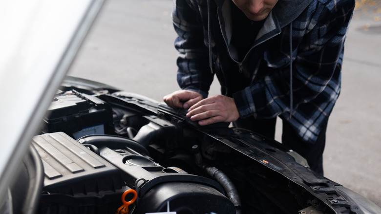 man looking at car engine
