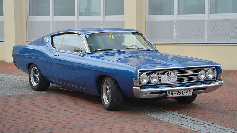 A blue 1968 Ford Torino in front of a building, front 3/4 view