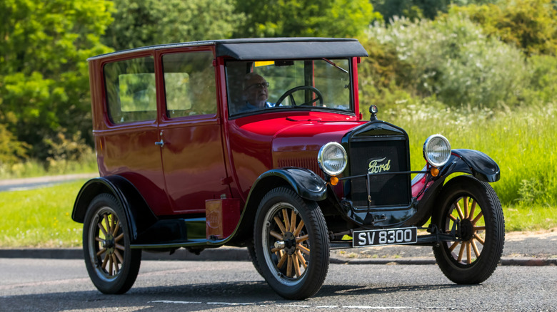 Man in red Ford Model T on country road