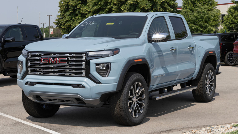 Front 3/4 view of blue-gray GMC Canyon pickup truck parked on dealership lot.