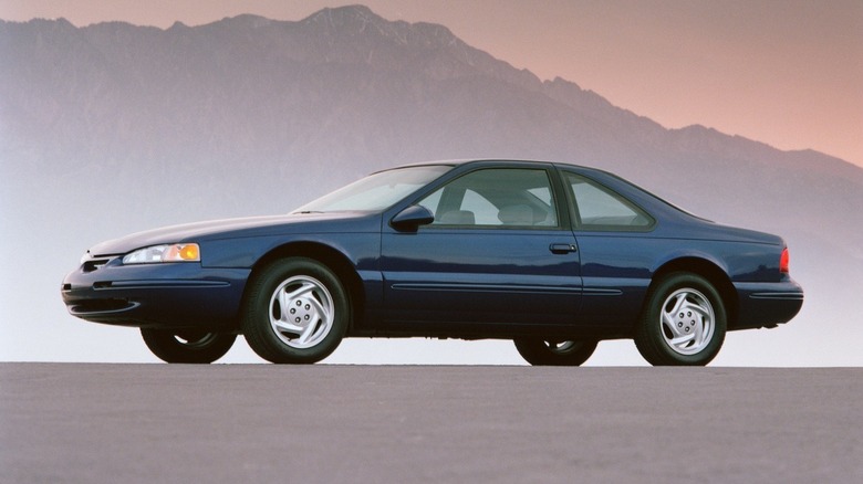 1996 Ford Thunderbird in blue, front 3/4 view, mountain in the background