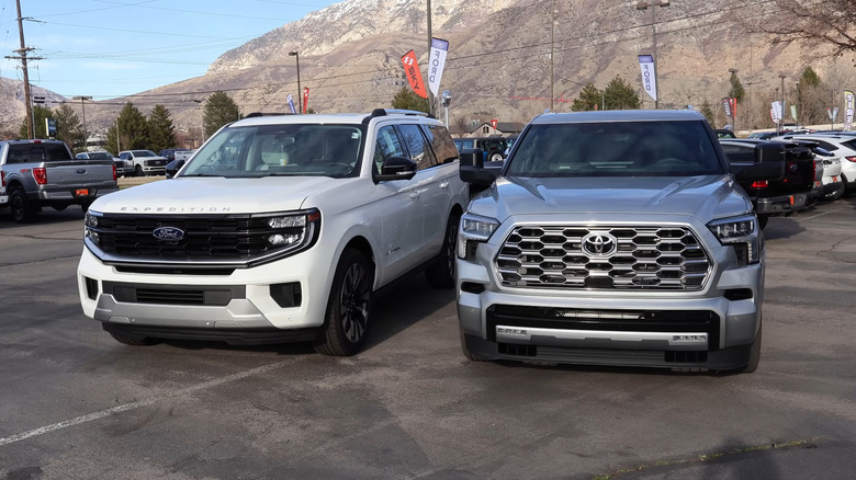 A Toyota 4Runner in silver standing next to a Ford Explorer in white in an outdoor parking lot.