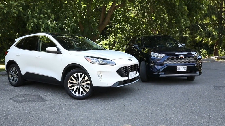 A white Ford Escape hybrid from 2021 standing at an angle next to a deep blue current-generation Toyota RAV4, both with Canadian plates on.