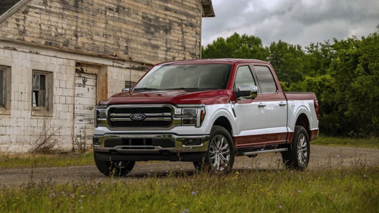 2027 Ford F-150 in two-tone paint parked on a rural dirt road in front of a dilapidated building