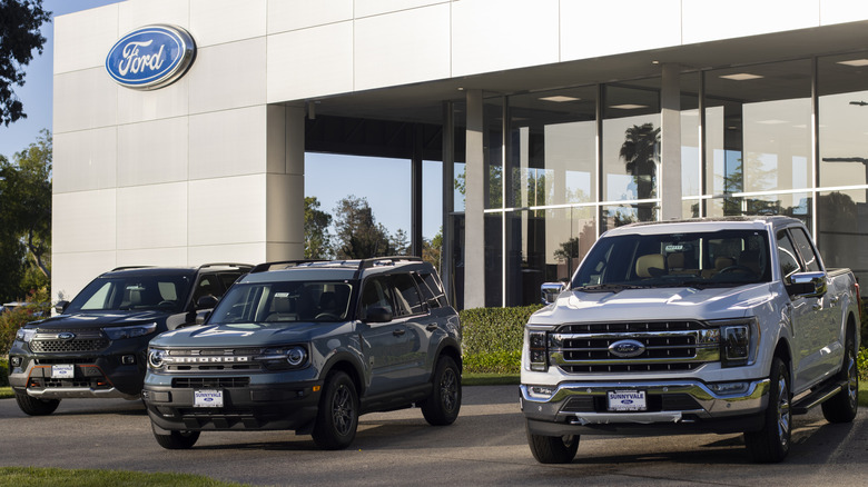 Front view of Ford F-150 pickup and SUVs parked in front of Ford dealership