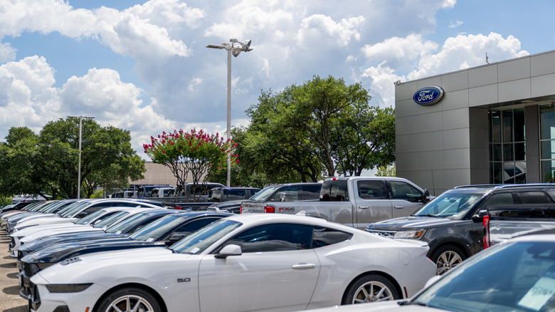 Side view of new Ford Mustangs and other Ford models parked in front Ford dealership in Texas.