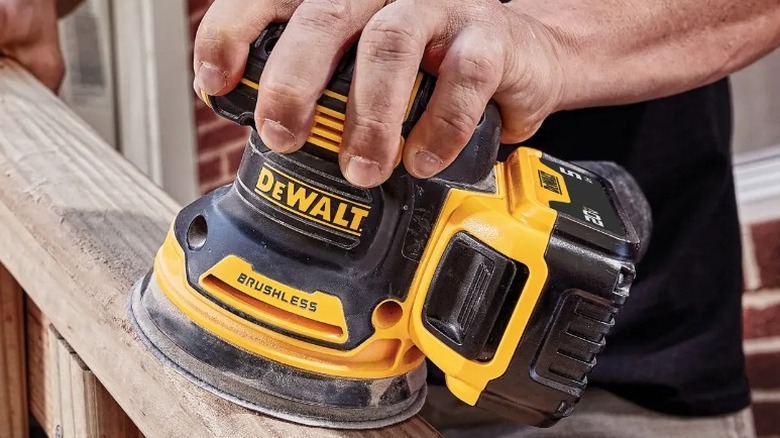 Person sanding deck rail with DeWalt 20V Max Orbital Sander