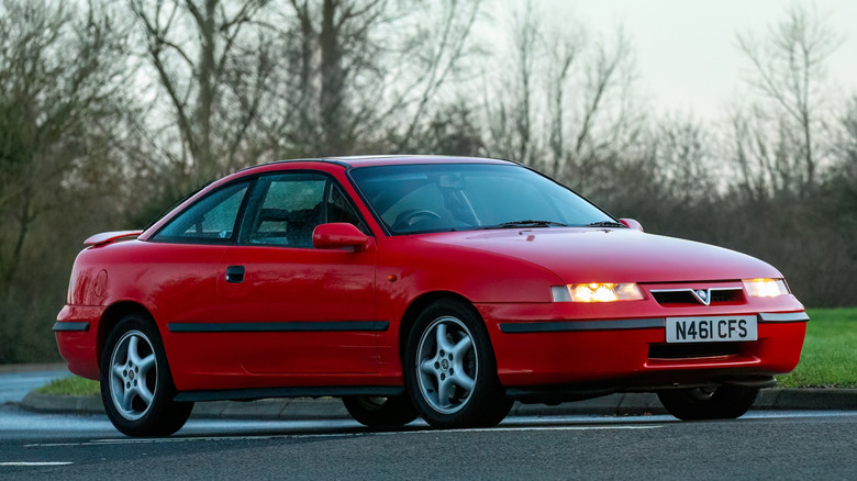 A Vauxhall Calibra in red driving, front 3/4 view