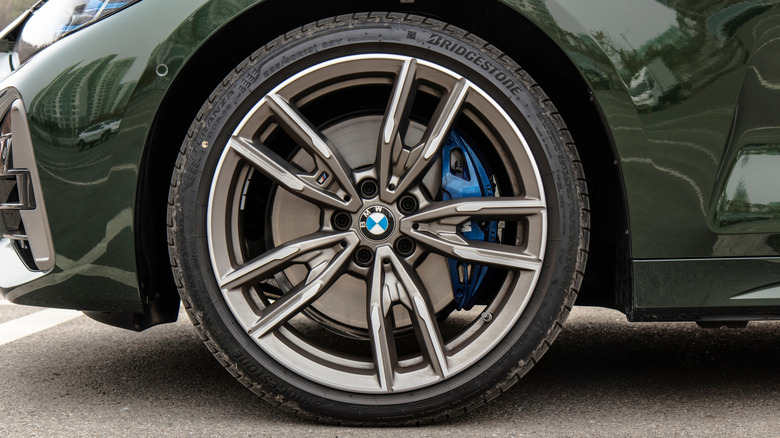 A close-up of a dark green BMW sedan wearing Bridgestone tires.