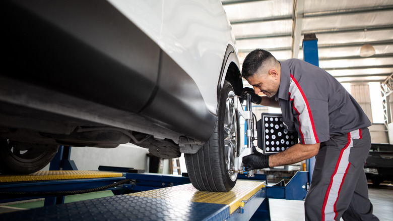 A mechanic in a shop aligning tires on a car.