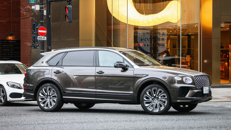 A gray Bentley Bentayga parked in front of a corporate office building in Japan.