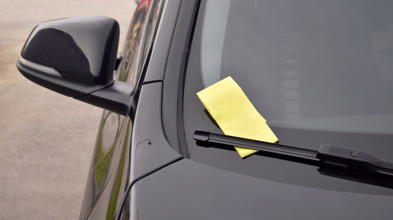 A yellow fine ticket placed on a car wiper