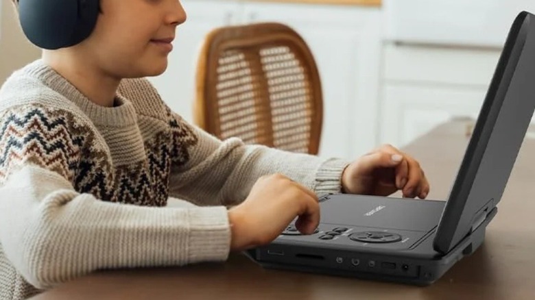 Child wearing headphones watching something on portable DVD player