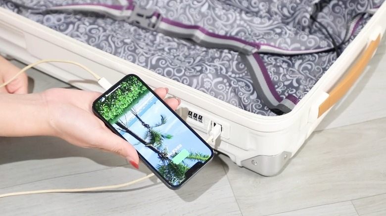 Person charging phone on USB charging port of a Joyway suitcase