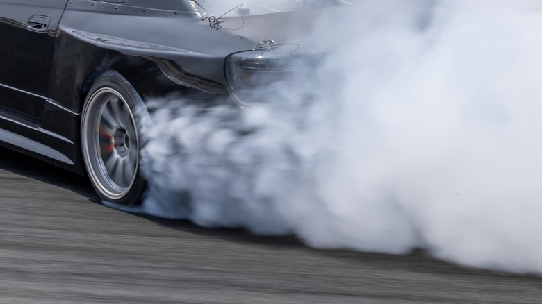 Black car doing burnouts with smoking rear wheels