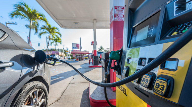 A gray car filling up at a gas station.