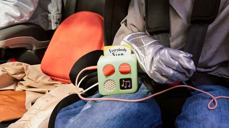 Child holding a blue box-like device with two orange knobs