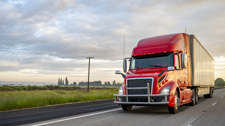A red semi-truck on a rural road