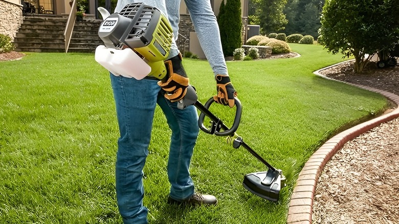 Person in long sleeves trimming grass with Ryobi string trimmer