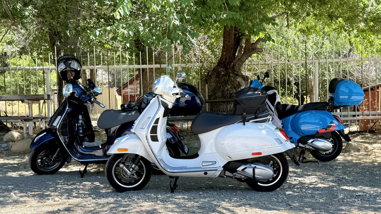 A group of Vespa 310 scooters parked in the shade