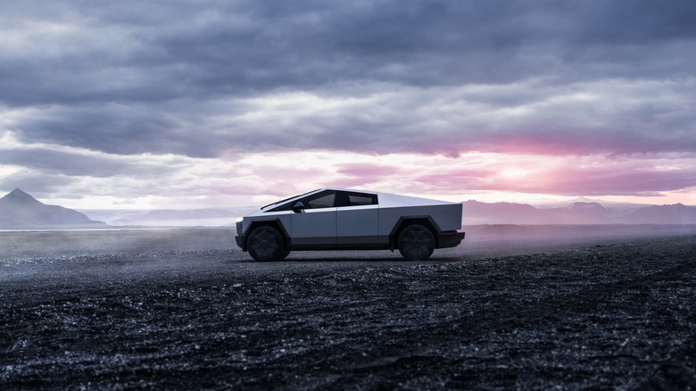 A parked Tesla in the wilderness with a sunset behind it
