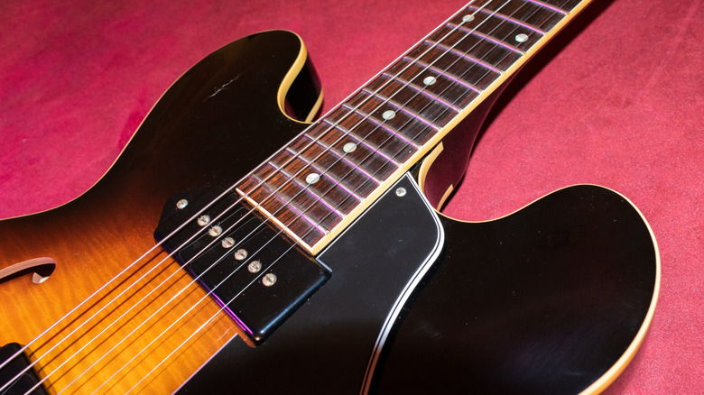 A close up short of the body, fret, and pickups of a Gibson ES 330 in mahogany sunburst.