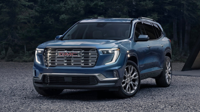 GMC Acadia parked on gravels with trees and a building in the background