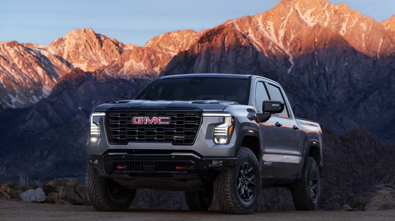 2027 GMC Sierra AT4X parked at sunrise with mountains in the background