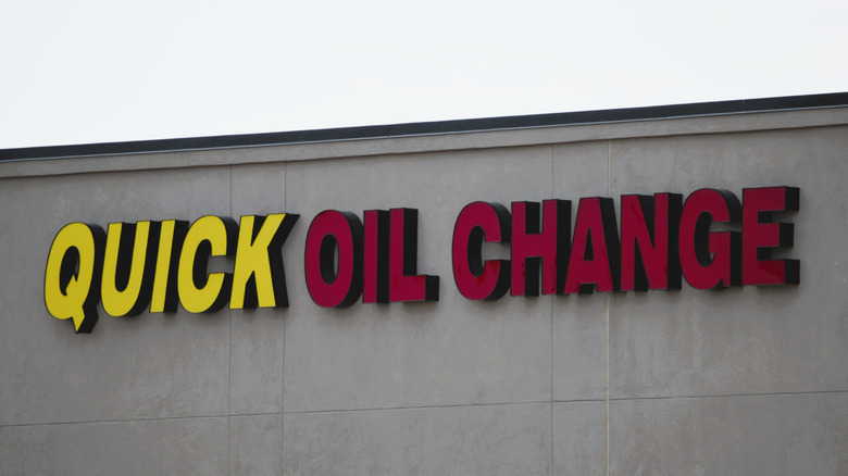 A yellow and red Quick Oil Change sign mounted on a building.