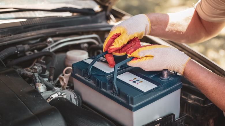 Mechanic inserting a new battery in a car.