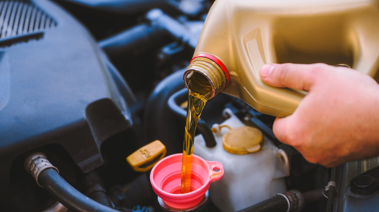 Pouring oil in a car's engine.