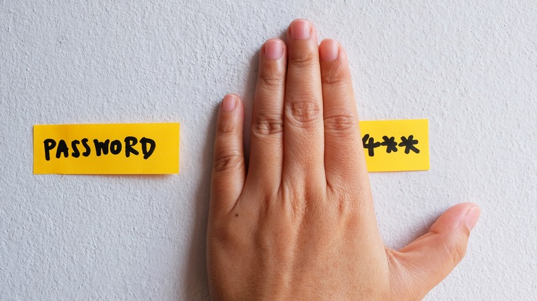 Hand covering password written on paper