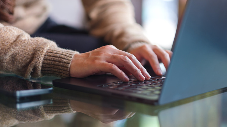 A closeup of a person typing on a laptop.