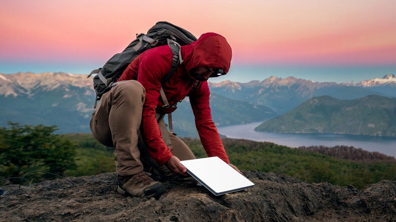Man on mountain installing Starlink mini on the ground