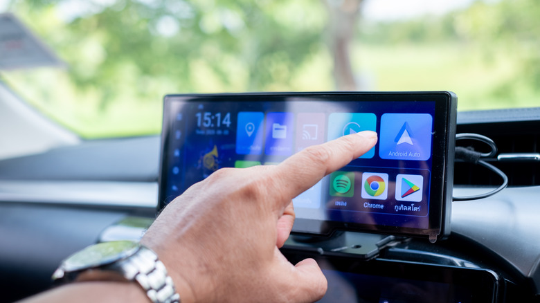 Person's hand manipulating modern car infotainment touchscreen system