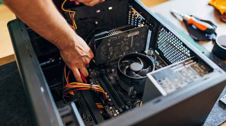 A person repairing the components inside a PC case