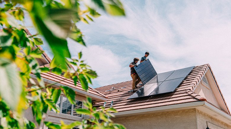 Installers installing solar panel on roof