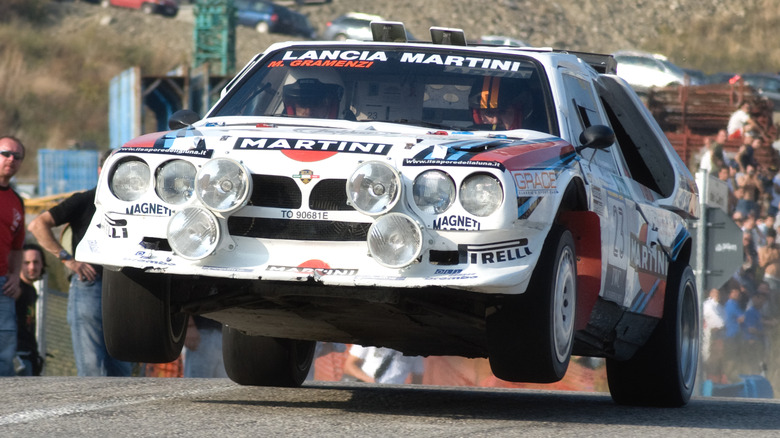 Front view of white Lancia S4 Group B rally car with front wheels off track