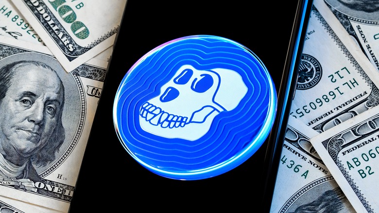 APE coin logo on phone in front of money pile