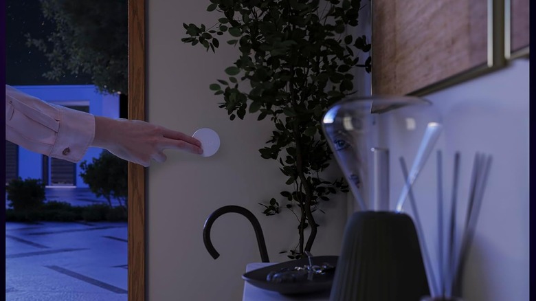 A person pressing a button on the wall near the front door.