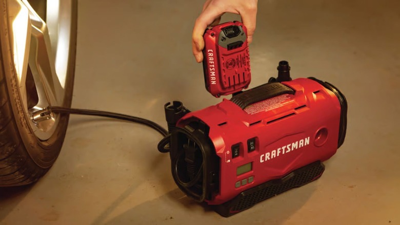 A person using a Craftsman Air Inflator to fill a vehicle tire