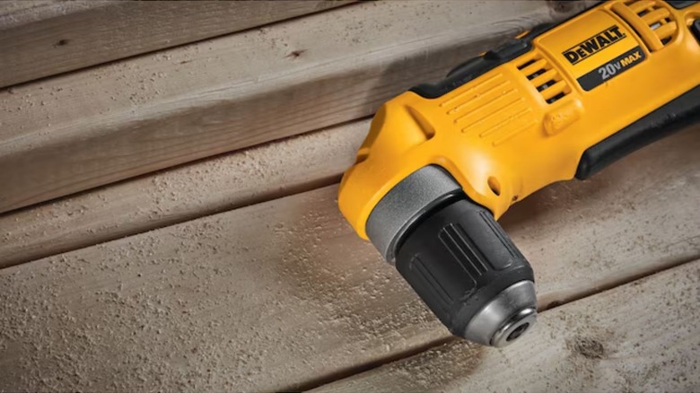 A DeWalt Right Angle Cordless Drill laid down on dusty wood planks